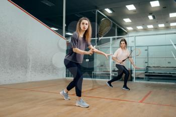 Two female players with squash racket playing on court. Girl on game training, active sport hobby, fitness workout for healthy lifestyle
