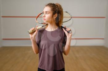Female player with squash racket in action. Girl on game training, active sport hobby on court