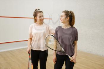Two smiling female squash players poses in locker room. Youth on training, active sport hobby, fitness workout for healthy lifestyle