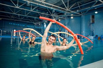 Male trainer and female group, aqua aerobics training in the pool. Man and women in the water, sport swimming fitness workout