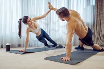 Morning fit workout of love couple at home. Active man and woman in sportswear doing push up exercise in their house, healthy lifestyle, physical culture