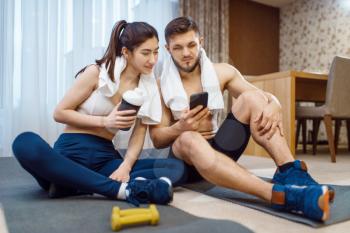 Beautiful love couple resting after fitness workout at home. Active man and woman in sportswear doing push up exercise in their house, healthy lifestyle, family physical culture