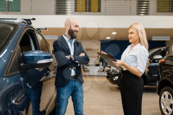 Smiling man and saleswoman in car dealership. Customer and seller in vehicle showroom, male person buying transport, auto dealer business