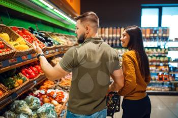 Couple with basket in grocery supermarket together. Man and woman buying fruits and vegetables in market, customers shopping food