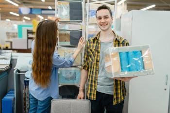 Young love couple choosing core of mattress in furniture store showroom. Man and woman looking samples for bedroom in shop, husband and wife buys goods for modern home interior