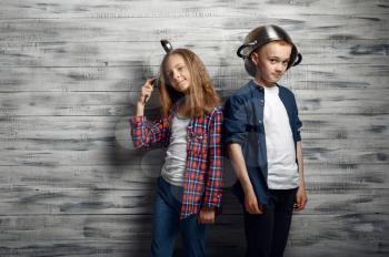 Little boy and girl poses with pot and the ladle in studio. Children play, kids isolated on wooden background, child photo session