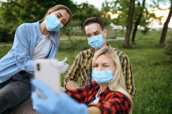 Young friends in masks and gloves makes selfie in park, quarantine. Female person walking during the epidemic, health care and protection, pandemic lifestyle