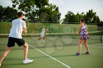 Mixed doubles tennis players, outdoor court. Active healthy lifestyle, people play sport game with racket and ball, fitness workout with racquets
