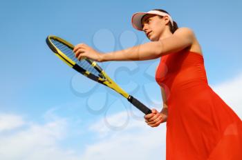 Female tennis player with racket prepares to hit the ball on outdoor court. Active healthy lifestyle, sport game competition, fitness training with racquet