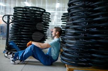 Male worker at the stack of bicycle wheels on a pallet on factory. Bike rims assembly line in workshop, cycle parts installation, modern technology
