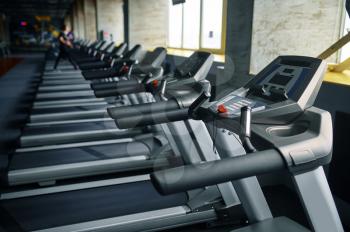 Row of treadmills in gym, running machine, nobody. Equipment for cardio trainings and health care, sport club interior