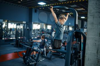 Boy on exercise machine, fitness training in gym. Youngster in sport club, healthcare and healthy lifestyle, schoolboy on workout, sportive youth