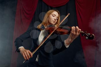 Female violonist with bow and violin, performance on stage. Woman with string musical instrument, music art, musician play on viola, dark background