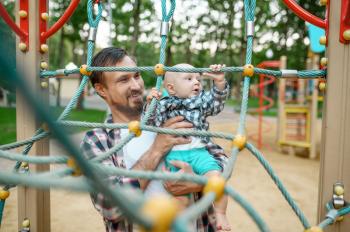 Father with his little son on playground in summer park. Dad play with male baby, vacations with child, family happiness