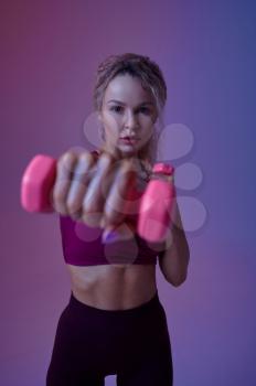 Young sexy sportswoman with dumbbells poses in studio, neon background. Fitness woman at the photo shoot, sport concept, active lifestyle motivation