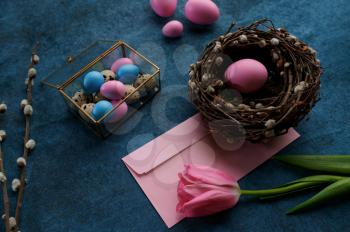 Willow branch and tulip, easter eggs, decorative gift box and nest on blue cloth background. Spring tree blooming and paschal food, fresh floral decoration for holiday celebration, event symbol