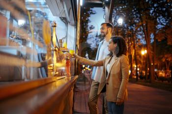 Love couple buying coffee in city amusement park. Man and woman relax outdoors. Family leisures in summertime, entertainment theme