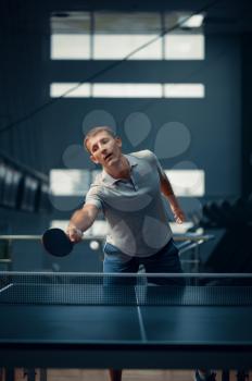 Man hits the ball at the net, table tennis, ping pong player. Sportsman playing table-tennis indoors, sport game with racket, active healthy lifestyle
