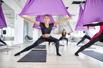 Fly yoga, female group training with hammocks. Fitness, pilates and dance exercises mix. Women on yogi workout in sports studio
