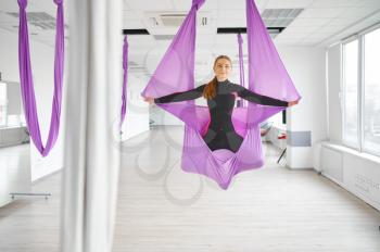 Aerial or antigravity yoga, group training, hanging on hammocks. Fitness, pilates and dance exercises mix. Women on yoga workout in gym, fit lifestyle
