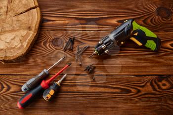 Screwdrivers and self tapping screws on stump, closeup, wooden background, nobody. Professional instrument, carpenter equipment, woodwork tools