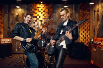 Two artists with electric guitars, music performing on stage. Rock band performance or repetition in garage, man with musical instrument, live music