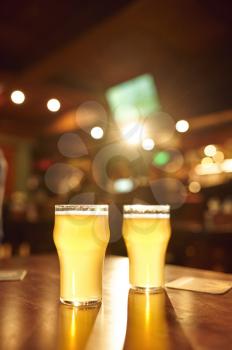 Two glasses full of fresh foamy beer on wooden counter in bar, nobody. Pub theme concept, night lifestyle, nightstyle symbol, restaurant interior on background