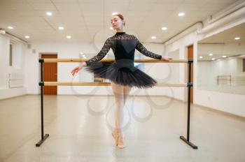 Ballerina poses at the barre in class. Ballet school, female dancers on choreography lesson, girls practicing grace dance