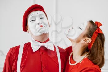 Two mime artists in red costumes, kissing scene. Pantomime theater, parody comedian, positive emotion, humour performance, funny face mimic and grimace