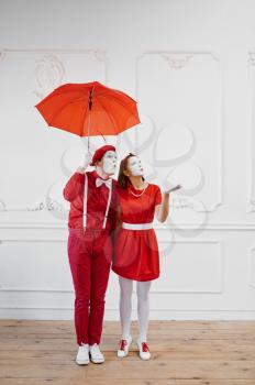 Mime artists, scene with umbrella in rainy weather. Pantomime theater, parody comedian, positive emotion, humour performance, funny face mimic and grimace