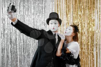 Two mime artists, lady poses at gentleman with camera. Pantomime theater, parody comedian, positive emotion, humour performance, funny face mimic and grimace