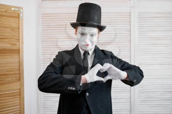 Male mime artist, love heart gesture, parody. Pantomime theater, comedian, positive emotion, humour performance, funny face mimic and grimace