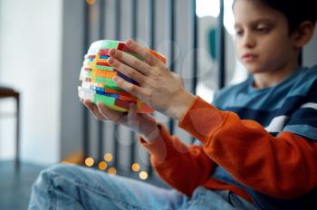 Child trying to solve difficult puzzle cube. Toy for brain and logical mind training, creative game, solving of complex problems