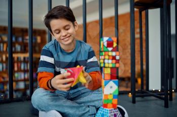 Happy little boy play with puzzle cubes. Toy for brain and logical mind training, creative game, solving of complex problems