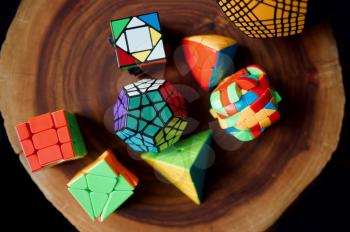 Different colorful puzzle cubes on wooden stump, top view, nobody. Toy for brain and logical mind training, creative game, solving of complex problems
