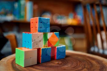 Different colorful puzzle cubes on wooden stump, closeup view, nobody. Toy for brain and logical mind training, creative game, solving of complex problems