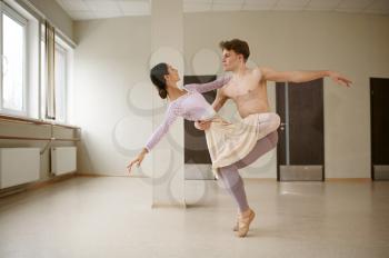Couple of ballet dancers, dancing in action. Ballerina with partner training in class, dance studio interior