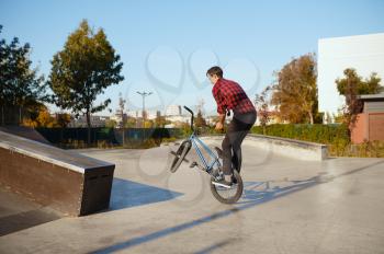 Male bmx biker doing trick, training in skatepark. Extreme bicycle sport, dangerous cycle exercise, risk street riding, biking in summer park