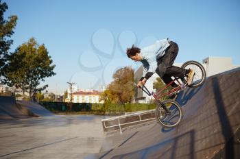 Bmx biker doing trick on ramp,teenager on training in skatepark. Extreme bicycle sport, dangerous cycle exercise, risk street riding, biking in summer park