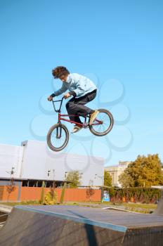 Male bmx biker doing trick on ramp,teenager on training in skatepark. Extreme bicycle sport, dangerous cycle exercise, risk street riding, biking in summer park