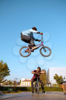 Bmx biker on ramp, jump in action, training in skatepark. Extreme bicycle sport, dangerous cycle exercise, street riding, teens biking in summer park