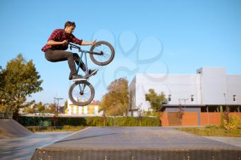 Male bmx biker jumps on ramp,teenager on training in skatepark. Extreme bicycle sport, dangerous cycle exercise, risk street riding, biking in summer park