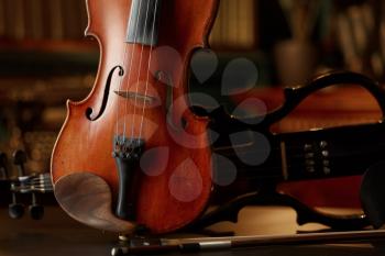 Violin in retro style and modern electric viola, closeup view, nobody. Two classical string musical instruments, music art, dark background