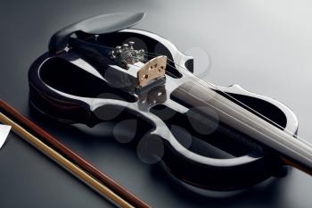 Modern electric violin and bow, closeup view, nobody. Classical string musical instrument, black background, electro viola