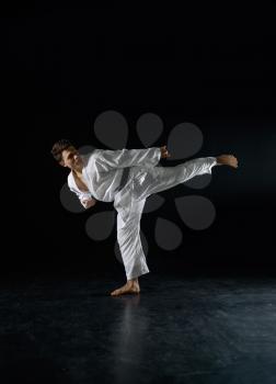 Male karateka, fighter in a combat stance, dark background. Man on karate workout, martial arts, fighting competition