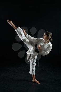 Male karate fighter in white kimono, combat stance in action, dark background. Karateka on workout, martial arts, training before fighting competition