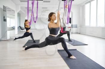 Aerial or anti-gravity yoga, group training, hanging on hammocks. Fitness, pilates and dance exercises mix. Women on yogi workout in gym, fit lifestyle