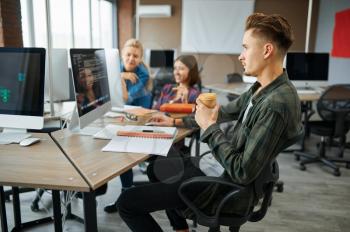 Young IT specialists works on computers in office. Web programmer or designer at workplace, creative occupation. Modern information technology, corporate team