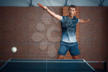 Man hits the ball, table tennis, ping pong player. Sportsman playing table-tennis indoors, sport game with racket, active healthy lifestyle