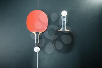 Ping pong balls and rackets at the net, top view, nobody, table tennis concept. Table-tennis indoors, sport game motivation, active healthy lifestyle, pingpong